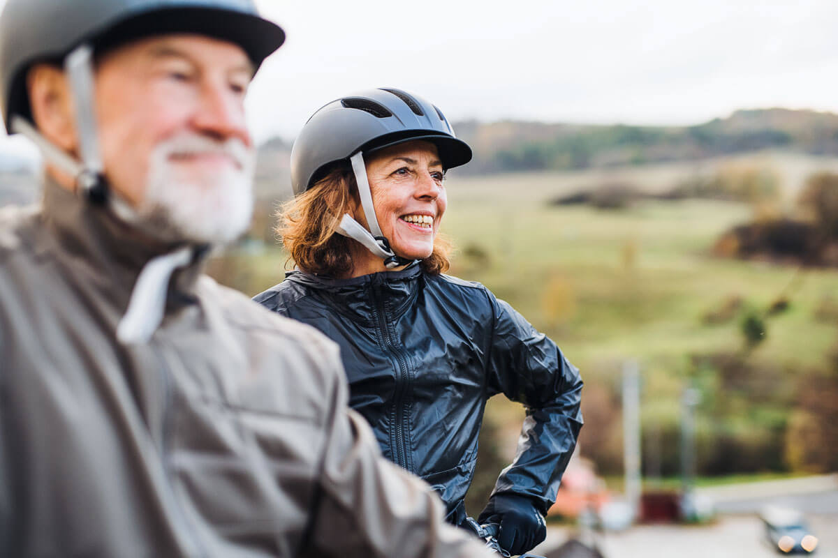 Two adults in cycling helmets with hills and fields in the distance.