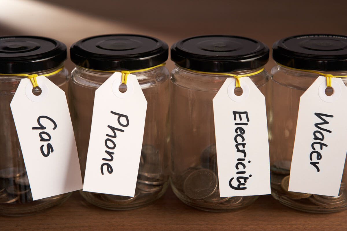 Four empty jam jars, labelled 'Gas', 'Phone', 'Electricity', 'Water'.