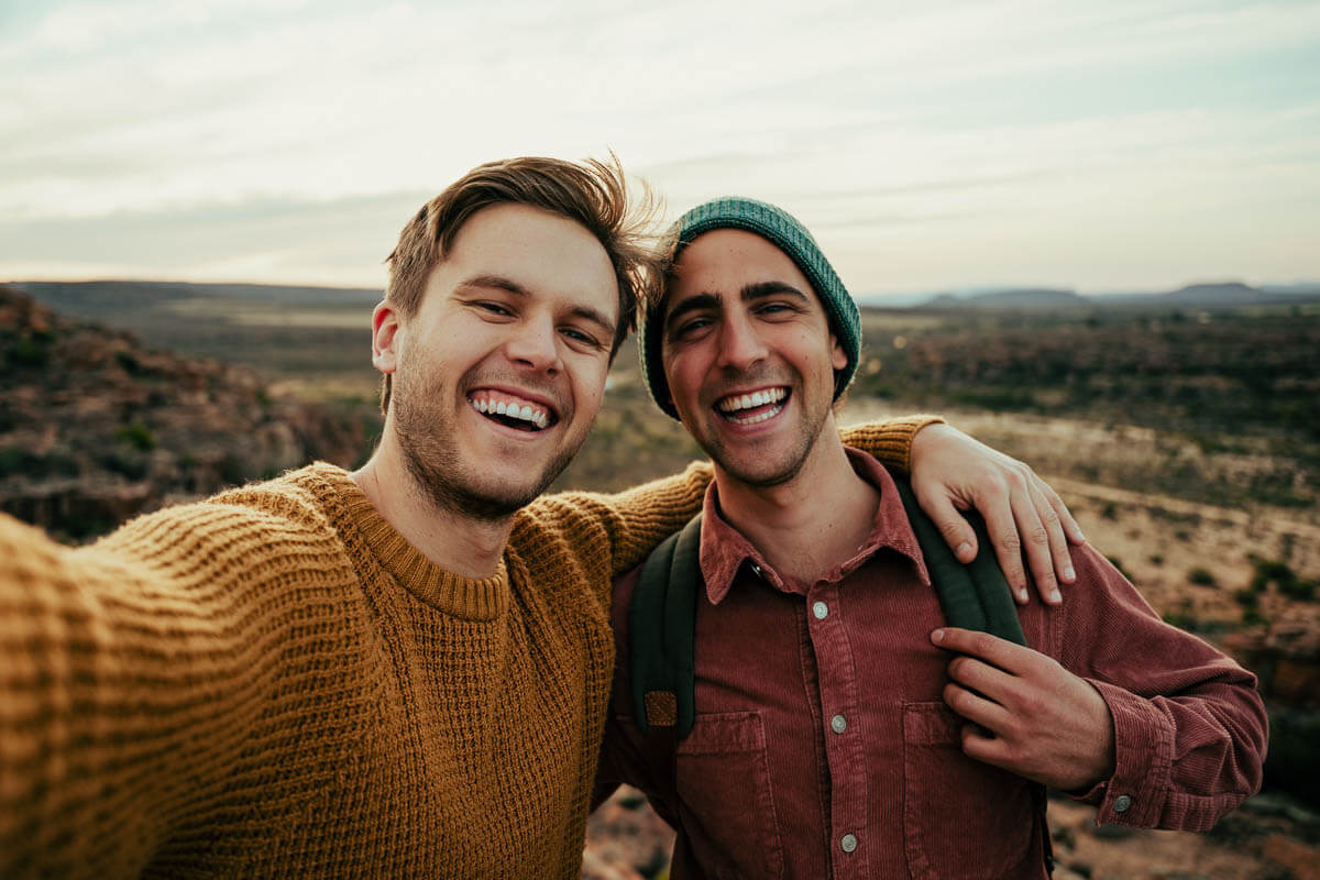 Two smiling people taking a selfie while out on a hike